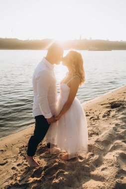 Güzel bir çiftin gün batımında düğün fotoğrafları, beyaz elbiseli gelin, beyaz gömlekli ve siyah pantolonlu damat.