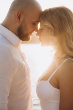 Güzel bir çiftin gün batımında düğün fotoğrafları, beyaz elbiseli gelin, beyaz gömlekli ve siyah pantolonlu damat.