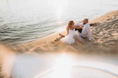 Güzel bir çiftin gün batımında düğün fotoğrafları, beyaz elbiseli gelin, beyaz gömlekli ve siyah pantolonlu damat.