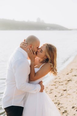 Wedding photosession at sunset of a beautiful couple, the bride in a white dress, and the groom in a white shirt and black trousers