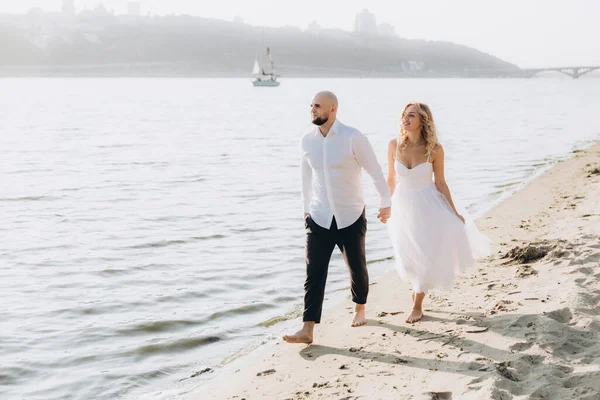 Güzel bir çiftin gün batımında düğün fotoğrafları, beyaz elbiseli gelin, beyaz gömlekli ve siyah pantolonlu damat.