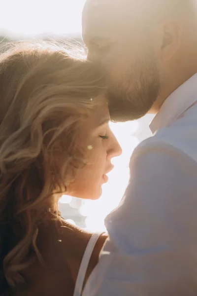 Güzel bir çiftin gün batımında düğün fotoğrafları, beyaz elbiseli gelin, beyaz gömlekli ve siyah pantolonlu damat.