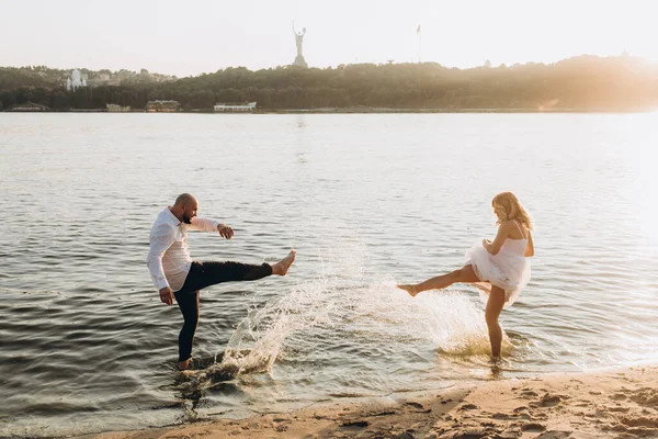Güzel bir çiftin gün batımında düğün fotoğrafları, beyaz elbiseli gelin, beyaz gömlekli ve siyah pantolonlu damat.