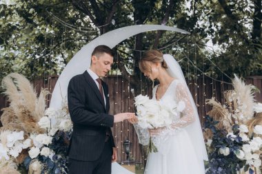 Şık bir çiftin yaz aylarında güzel bir uzay nikahı, takım elbiseli bir damat ve beyaz bir gelinlik içinde gelin..