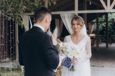 Şık bir çiftin yaz aylarında güzel bir uzay nikahı, takım elbiseli bir damat ve beyaz bir gelinlik içinde gelin..