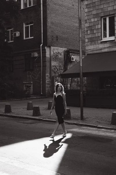 stock image A beautiful girl with a hairstyle in a black dress on the street with a cigarette in her hands smokes, black and white photo.