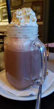 Bir bardak sıcak çikolata, krem şanti, kırılgan ve pipet.