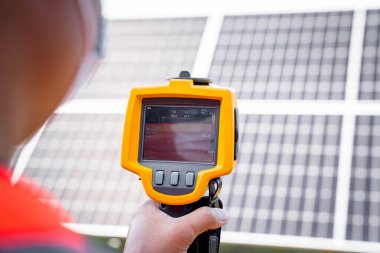 The technician takes the Thermoscan(thermal image camera) scan to the solar panel to check the hot spots in the cell, Concept to use technology to check the damage in the Solar plant.