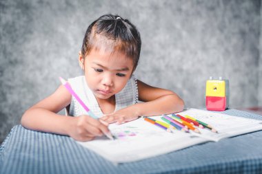 A girl learning to paint on a book She is passionate and fun in learning about art, concepts for learning about colors, and training the hand muscles.