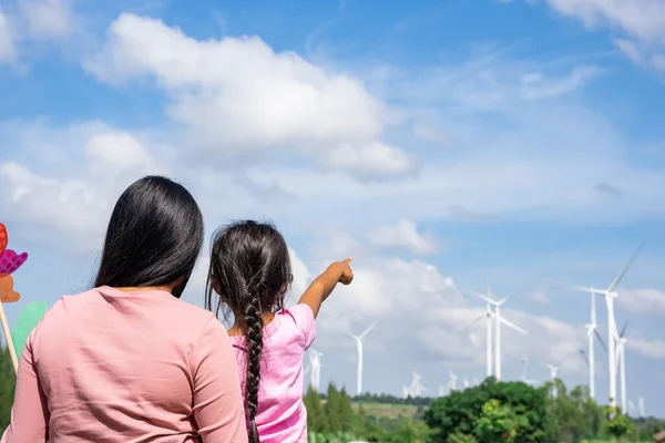 Wind turbines are an alternative electricity source to be sustainable resources in the future. People in the community with wind generators turbines. Clean energy concept saves the world.