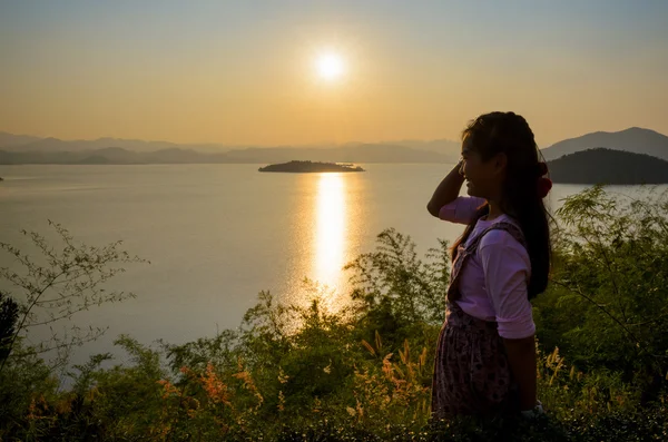 Happy young woman standing watching the sunset over the lake — Stock Photo, Image