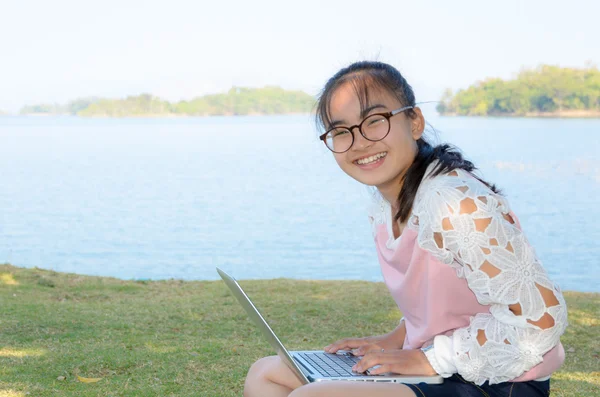 年轻的女孩，用在草地上的笔记本电脑 — 图库照片