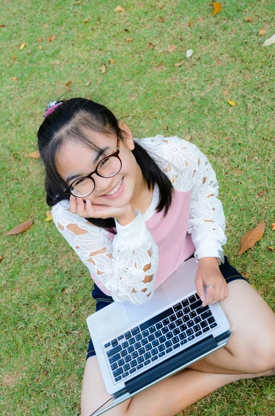 Chica encantadora con un ordenador portátil en la hierba —  Fotos de Stock