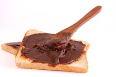 Beyaz arka planda ekmek ile çikolata yayılmış.