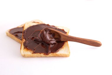 Beyaz arka planda ekmek ile çikolata yayılmış.
