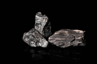 Makro, siyah yansıtıcı arka planda izole edilmiş hammadde Manganez Ore kayasının görüntüsünü kapat