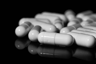 Makro, siyah arka planda beyaz ağrı kesici kapsülünü kapat.