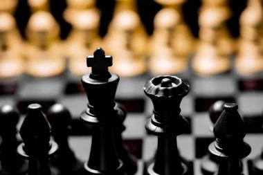 Yansıtıcı ayna yüzeyindeki siyah arkaplanı olan satranç taşlarını kapat