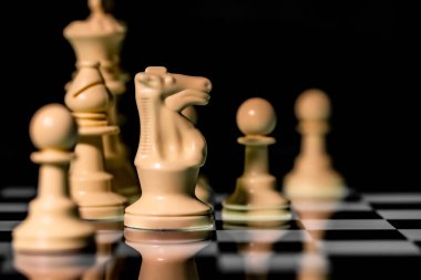 Yansıtıcı ayna yüzeyindeki siyah arkaplanı olan satranç taşlarını kapat