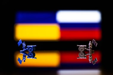 Rusya ve Ukrayna arasındaki savaşın kavramsal görüntüsü oyuncak askerler ve yansıtıcı bir arka plan üzerinde ulusal bayraklar kullanılıyor.