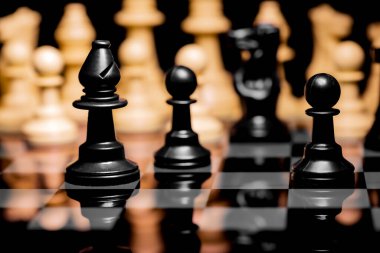 Yansıtıcı ayna yüzeyindeki siyah arkaplanı olan satranç taşlarını kapat