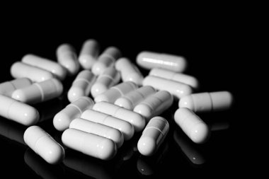 Makro, siyah arka planda beyaz ağrı kesici kapsülünü kapat.