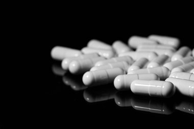 Makro, siyah arka planda beyaz ağrı kesici kapsülünü kapat.