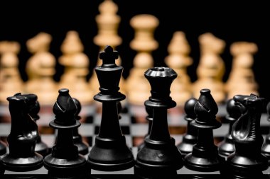 Yansıtıcı ayna yüzeyindeki siyah arkaplanı olan satranç taşlarını kapat