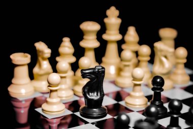 Yansıtıcı ayna yüzeyindeki siyah arkaplanı olan satranç taşlarını kapat