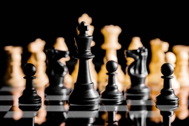 Yansıtıcı ayna yüzeyindeki siyah arkaplanı olan satranç taşlarını kapat