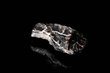 Makro, siyah yansıtıcı arka planda izole edilmiş hammadde Manganez Ore kayasının görüntüsünü kapat