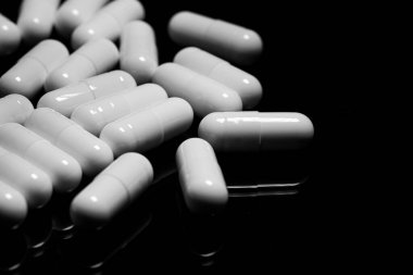 Makro, siyah arka planda beyaz ağrı kesici kapsülünü kapat.