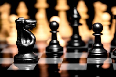 Yansıtıcı ayna yüzeyindeki siyah arkaplanı olan satranç taşlarını kapat