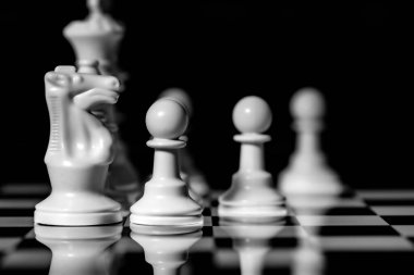 Yansıtıcı ayna yüzeyindeki siyah arkaplanı olan satranç taşlarını kapat