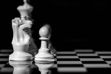 Yansıtıcı ayna yüzeyindeki siyah arkaplanı olan satranç taşlarını kapat