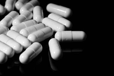 Makro, siyah arka planda beyaz ağrı kesici kapsülünü kapat.