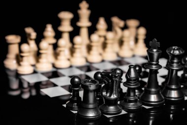 Yansıtıcı ayna yüzeyindeki siyah arkaplanı olan satranç taşlarını kapat