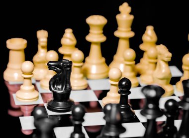 Yansıtıcı ayna yüzeyindeki siyah arkaplanı olan satranç taşlarını kapat