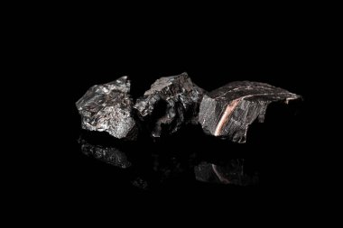 Makro, siyah yansıtıcı arka planda izole edilmiş hammadde Manganez Ore kayasının görüntüsünü kapat