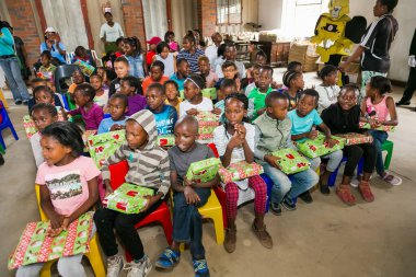 Johannesburg, Güney Afrika - 15 Aralık 2016: Genç Afrikalı okul çocukları Noel hediyelerini açıyor