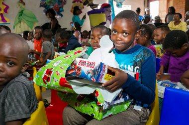 Johannesburg, Güney Afrika - 15 Aralık 2016: Genç Afrikalı okul çocukları Noel hediyelerini açıyor