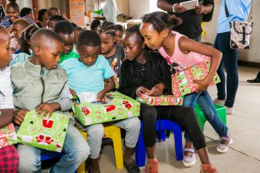 Johannesburg, Güney Afrika - 15 Aralık 2016: Genç Afrikalı okul çocukları Noel hediyelerini açıyor