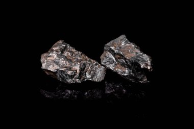 Makro, siyah yansıtıcı arka planda izole edilmiş hammadde Manganez Ore kayasının görüntüsünü kapat