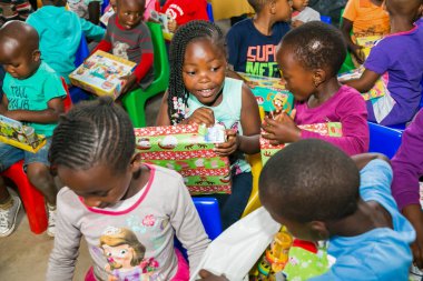 Johannesburg, Güney Afrika - 15 Aralık 2016: Genç Afrikalı okul çocukları Noel hediyelerini açıyor