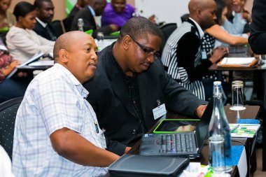 Johannesburg, South Africa - January 21, 2014: Diverse business persons going over data on digital devices at a meeting