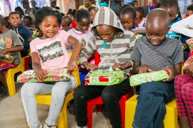 Johannesburg, Güney Afrika - 15 Aralık 2016: Genç Afrikalı okul çocukları Noel hediyelerini açıyor