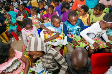 Johannesburg, Güney Afrika - 15 Aralık 2016: Genç Afrikalı okul çocukları Noel hediyelerini açıyor