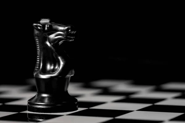 Close up of Chess pieces on a reflective mirror board surface with a plain black background