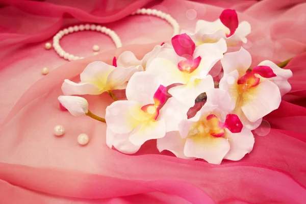 Orquídeas brancas bonitos, colar e contas em um fundo rosa macio — Fotografia de Stock