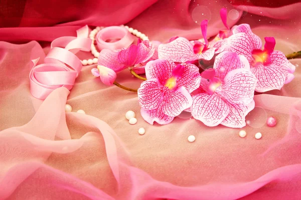 Różowa orchidea, naszyjnik, koraliki na miękki różowy tło — Zdjęcie stockowe